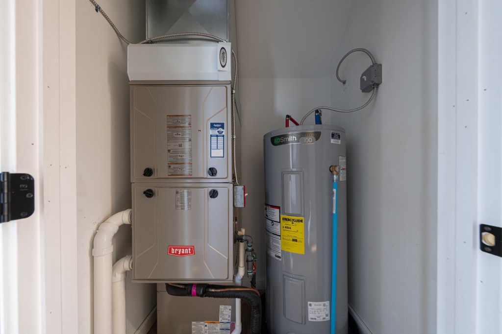A Bryant furnace/HVAC unit installed next to an A.O. Smith water heater in a utility closet.