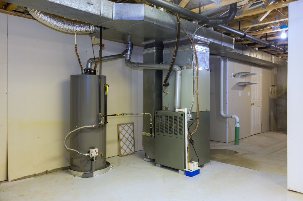 A furnace/HVAC unit and water heater in a basement utility room with exposed ductwork.